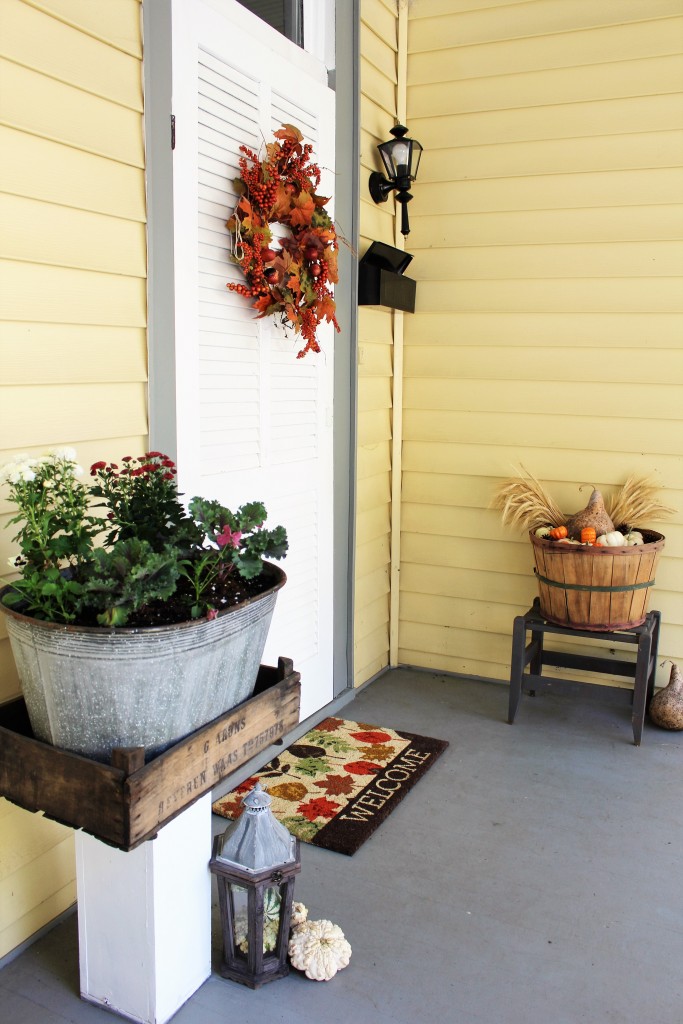 Fall entryway with white pumpkins, wheat, kale, mums, & rustic lantern and apple basket