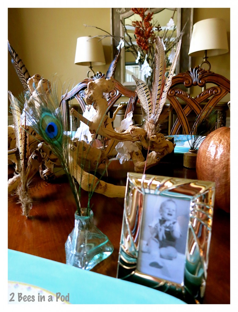 Vintage inkwells and framed vintage photographs compliment each place setting. The use of turquoise and copper brighten the dining room with this Fall tablescape. The peacock feathers add a touch of whimsy