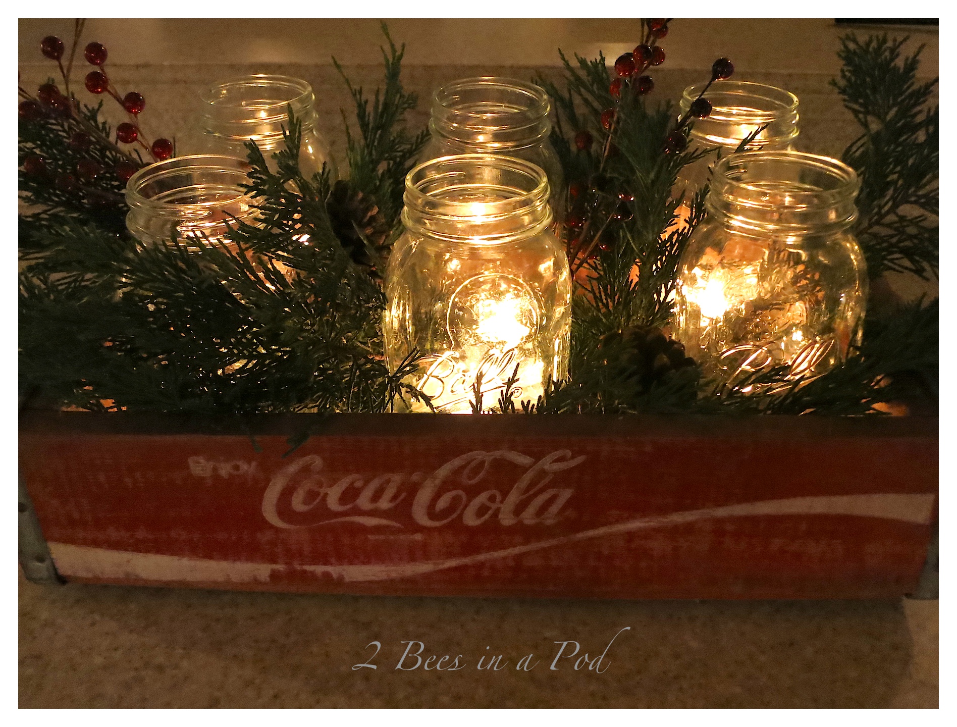 I used a vintage Coke crate as Christmas centerpiece by adding Mason jars, tea lights, evergreen, pinecones and berries