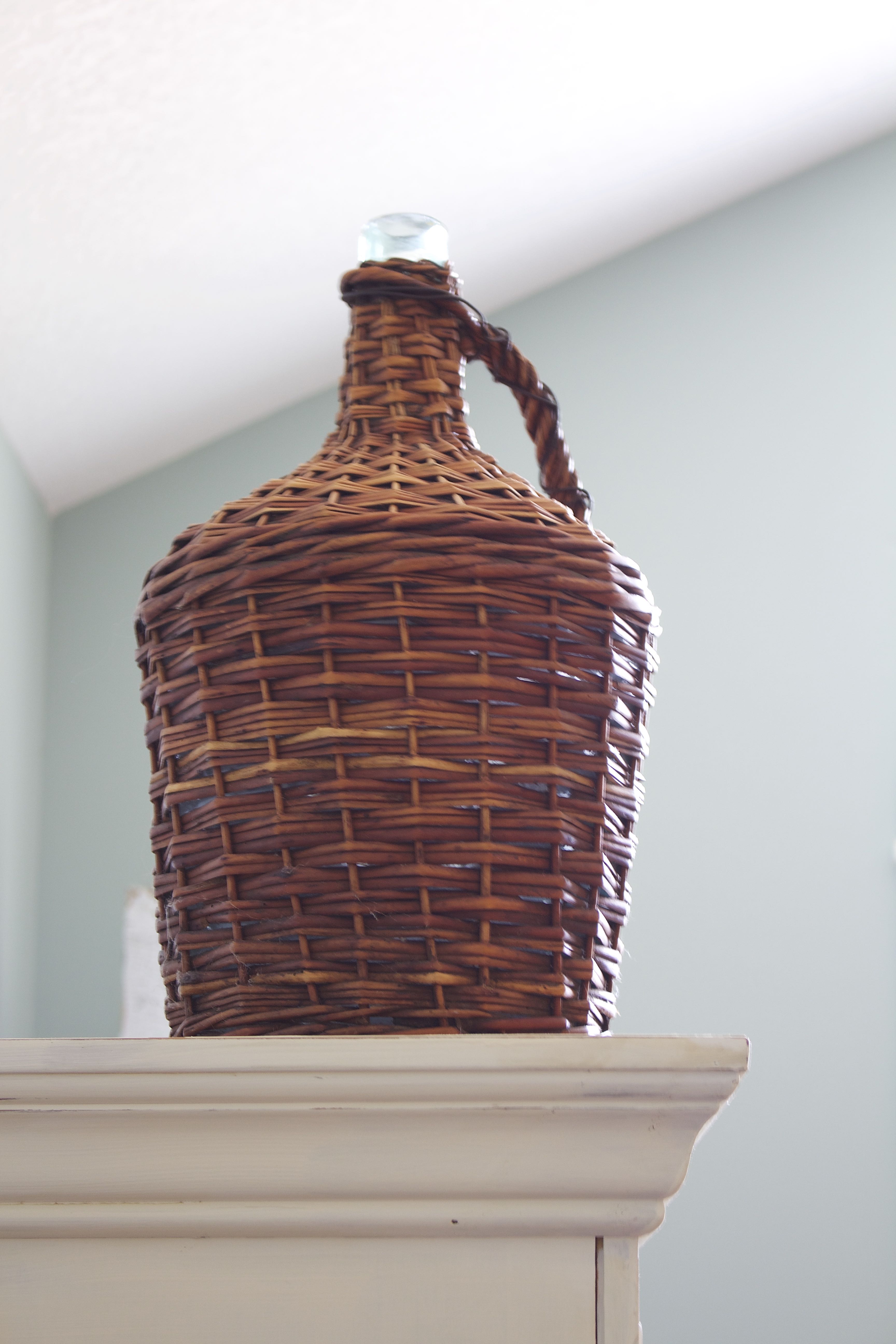  Hauteur ajoutée sur l'armoire peinte avec un panier à vin en osier vintage. Transformation d'armoire peinte à la craie.